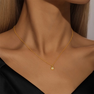 Close-up of gold teardrop necklace with sparkling zircon worn on a woman neck