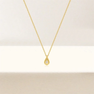 Close-up of a gold waterdrop pendant with a sparkling round zircon on a delicate chain