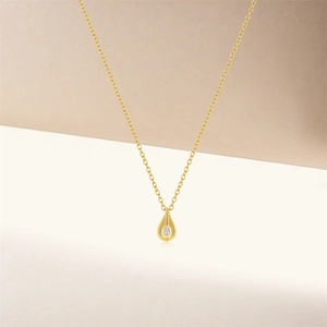 Detailed view of a gold teardrop pendant with a small sparkling diamond on a thin chain