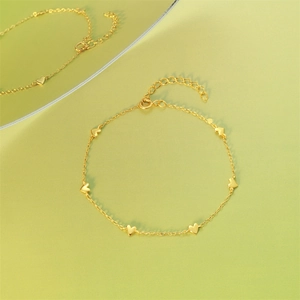 Close-up of gold heart charm bracelet with reflective mirror effect on green background