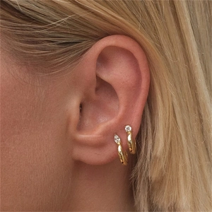 Close-up of minimalist gold vermeil huggie earrings with marquise and round zircon accents