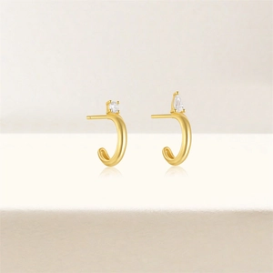 Detail of asymmetric 925 silver gold-plated studs with round and teardrop crystals
