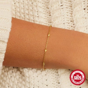 Minimalist S925 sterling silver gold heart bracelet worn on wrist over knit fabric
