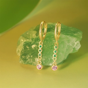 Detail of long gold earrings with three green stones and a pink crystal drop