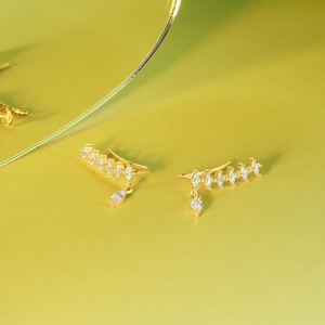 Detail von goldenen Ohrmanschetten mit funkelnden Zirkonia im Marquise-Schliff