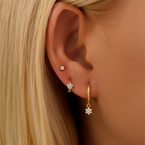 Close-up of a three-piece gold earring set with flower pendants and sparkling zircons