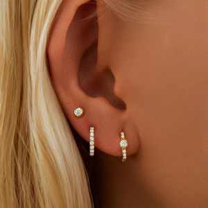 Macro shot of gold S925 sterling silver huggie earrings set with zircon studs on ear
