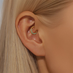Close-up of a gold-plated 925 silver daith piercing featuring seven turquoise stones
