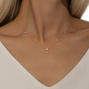 Detalle de collar de plata S925 dorada con colgantes florales y piedras de circón blanco