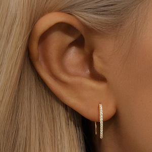 Close-up of gold-plated curved ear climber earrings featuring sparkling pavé zircon stones