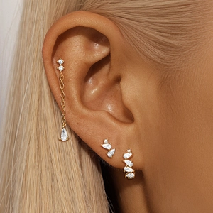 Close-up of gold s925 silver flower and star earring set with crystals on ear