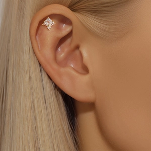 Detailed close-up of a gold star cartilage stud with white cubic zirconia on an ear