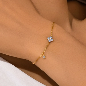 Detail of S925 silver gold bracelet with blue opal clover charm and zircon stone
