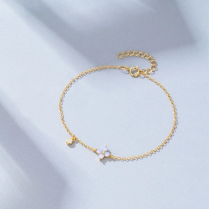 Close-up of gold-plated silver bracelet with blue opal clover and tiny zircon charm