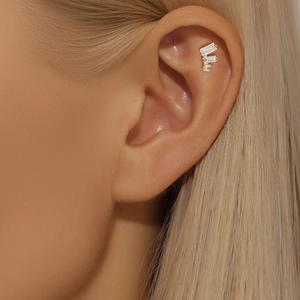 Close-up of gold s925 silver clover stud with baguette-cut zircons on the ear bone