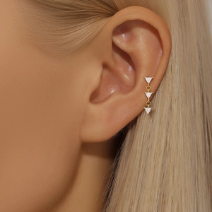 Close-up of triple triangle zircon gold ear studs worn on ear cartilage for minimalist style
