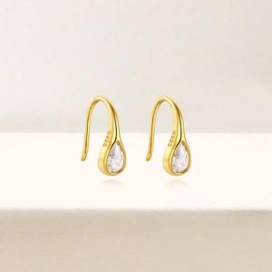 Detailed macro view of S925 hallmark on gold teardrop earrings with zircon stones