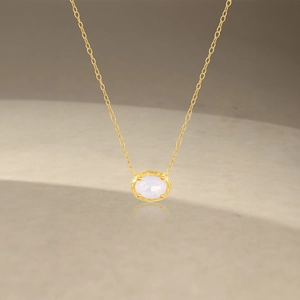 Detail of pink opal geometric necklace with textured gold setting on marble