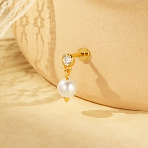 Macro view of gold S925 silver labret earring with sparkling zircon and round white pearl