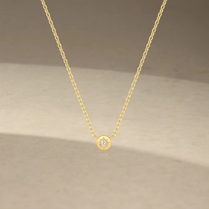 Detailed close-up of golden octagonal star zircon necklace on minimalist background