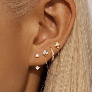 Detalle del set de pendientes de botón con borla triangular y trébol en plata 925 oro