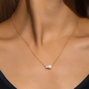 Primer plano de collar de plata S925 dorada con dos perlas en el cuello de una modelo