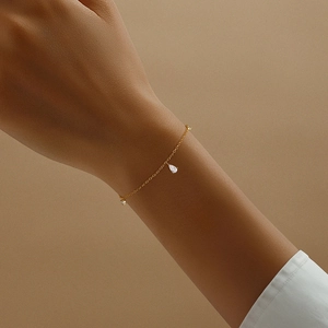 Dettaglio del bracciale in argento S925 dorato con ciondoli in zircone su polso donna