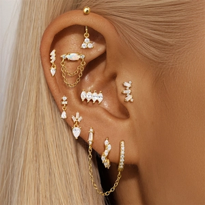Detailopname van een gouden piercingset met fonkelende zirkonia op het oor van een model