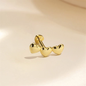 Macro view of gold-plated triple heart labret stud with a flat back cartilage design