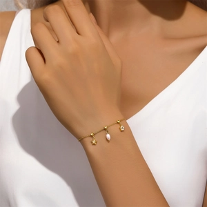 Détail d'un bracelet en argent doré orné de breloques étoile, perle et fleur