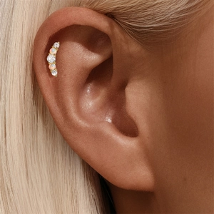 Close-up of gold ear stud with curved opal and white zircon stones on model ear