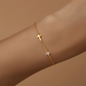 Detail von Goldkreuz und Diamantblumen-Anhängern an einem zarten S925 Silberarmband