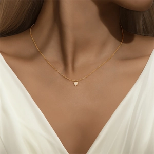 Detail van een minimalistische gouden hartketting met opaal gedragen door een model