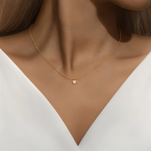 Detailopname van een hartvormige opaal hanger aan een dunne gouden ketting bij een model