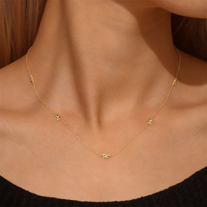 Vue détaillée des pendentifs nœuds dorés sur une fine chaîne en argent sterling S925
