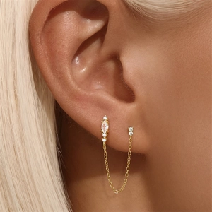 Close-up of gold chain earrings with marquise and round zircon crystals on model