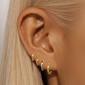 Makroansicht goldener S925 Silber Creolen im modernen Multi-Piercing-Stil getragen