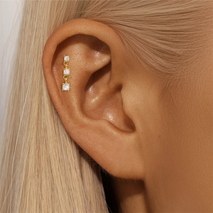 Close-up of three sparkling vertical cubic zirconia studs set in gold plating on the ear