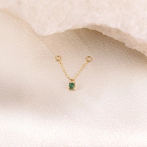 Macro detail of a 925 sterling silver chain with a central oval green gemstone charm