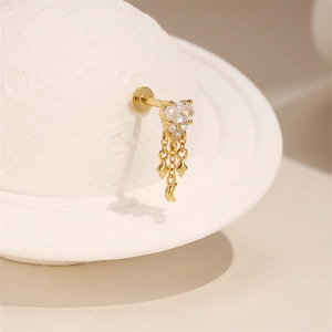 Detail of gold stud earring with white zircon, dangling moon and rhombus charms