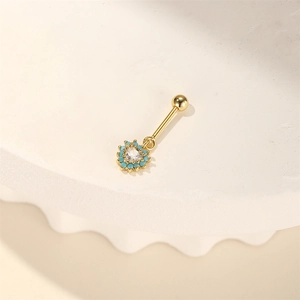 Detail van een hartvormige gouden navelpiercing met blauwe steentjes en helder zirkoon