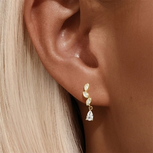 Close-up of gold drop earrings with marquise and teardrop zircons worn by a model