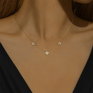 Close-up of a gold S925 sterling silver necklace with three zircon flower pendants on a model