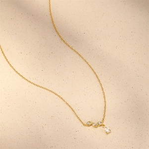 Macro detail of gold-plated necklace with teardrop and marquise cut crystal pendants