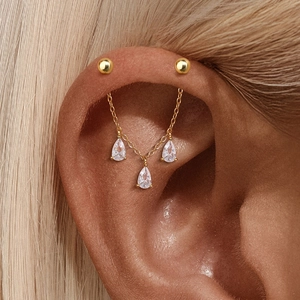 Close-up of a gold double stud chain earring with three pear-cut zircon drop charms