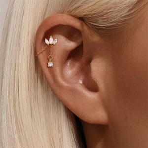 Macro detail of gold-plated tassel ear cuff with opal-like stone and zircon accents