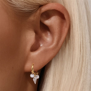 Close-up of gold fan-shaped hoop earrings with hanging clear zircon crystals on model