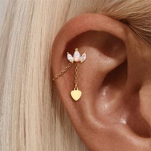 Detail of gold chain earring with opal drop, zircon stones, and hanging heart pendant