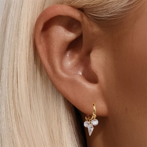 Close-up of gold drop earrings with tiered round and diamond-shaped zircons on model