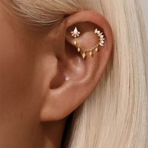 Detail of gold-plated silver chain earring with rhombus charms and white stones on ear